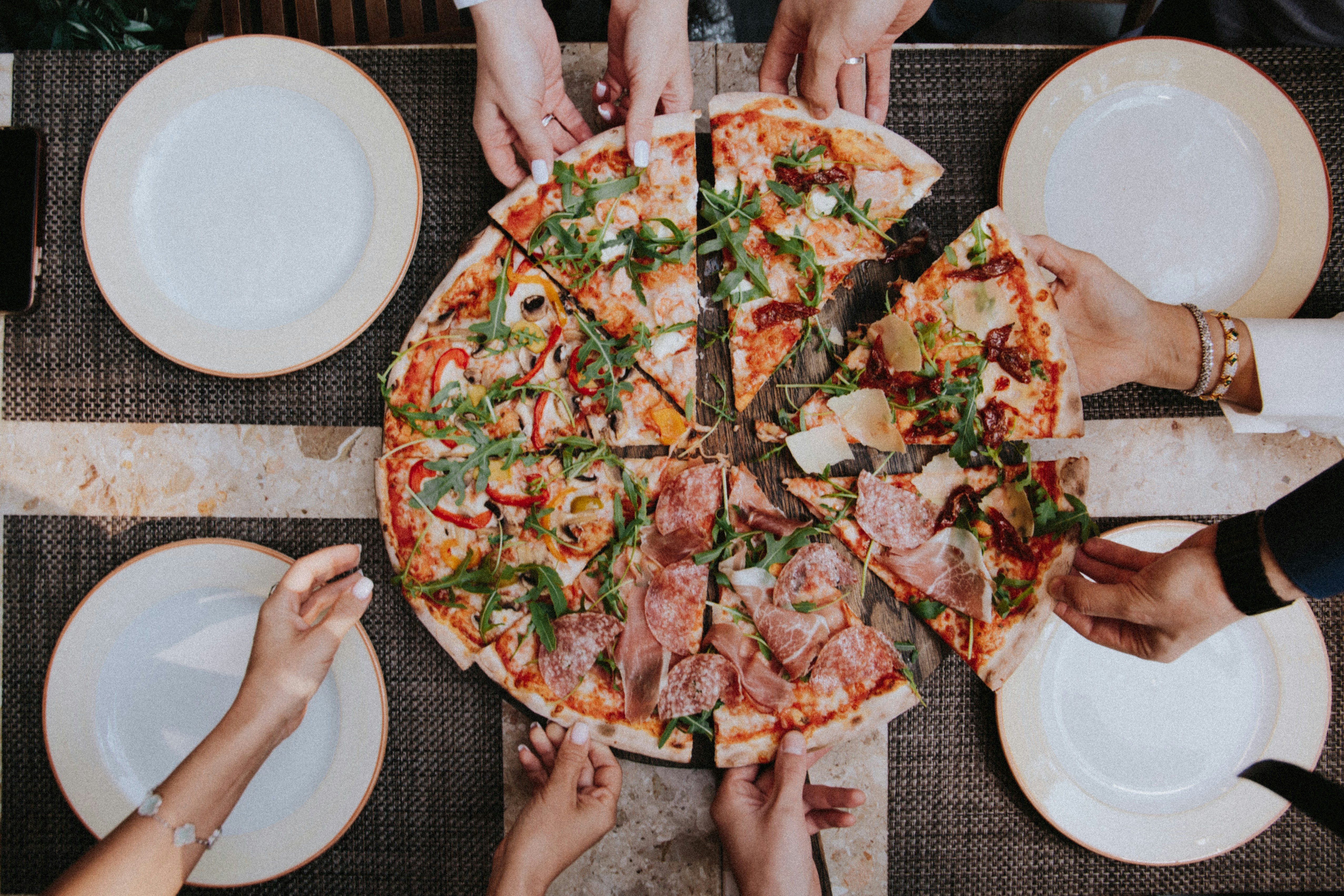 Pizza on plate with hands taking a piece